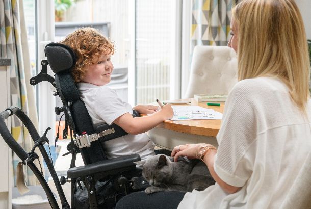 moeder met zoon in rolstoel zitten thuis aan tafel